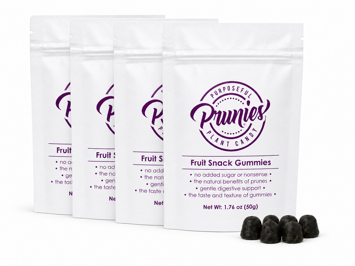 Four white stand-up pouches of Prunies Fruit Snack Gummies arranged in a row, with four dark purple gummies displayed in front on a white background.